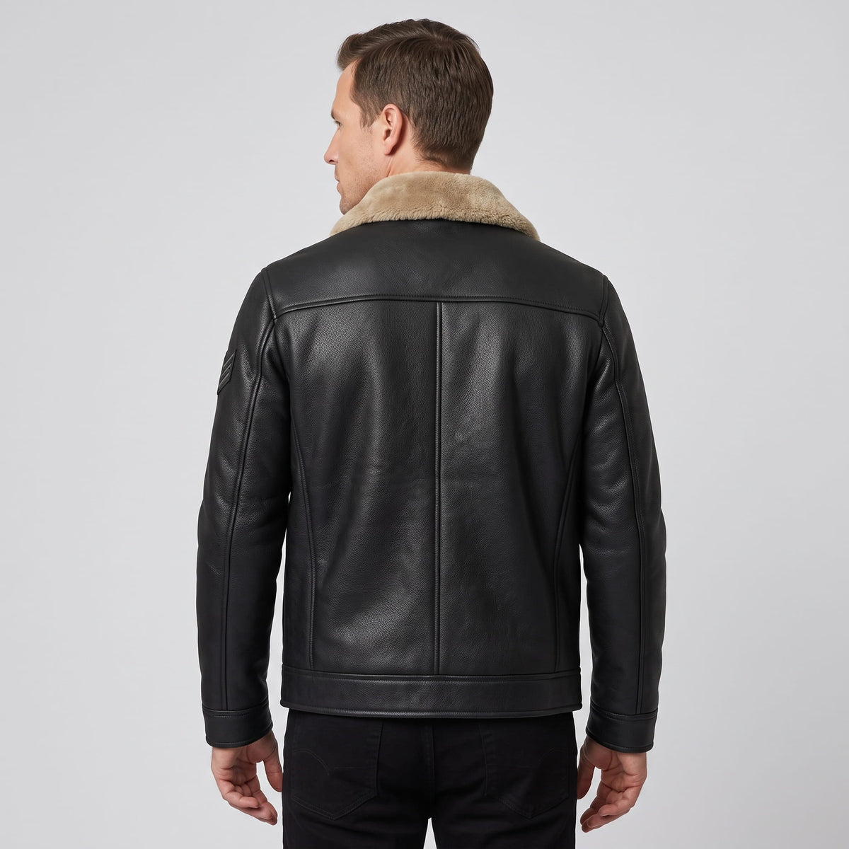 A man wearing a black leather shearling jacket with a plush collar, shown from the back