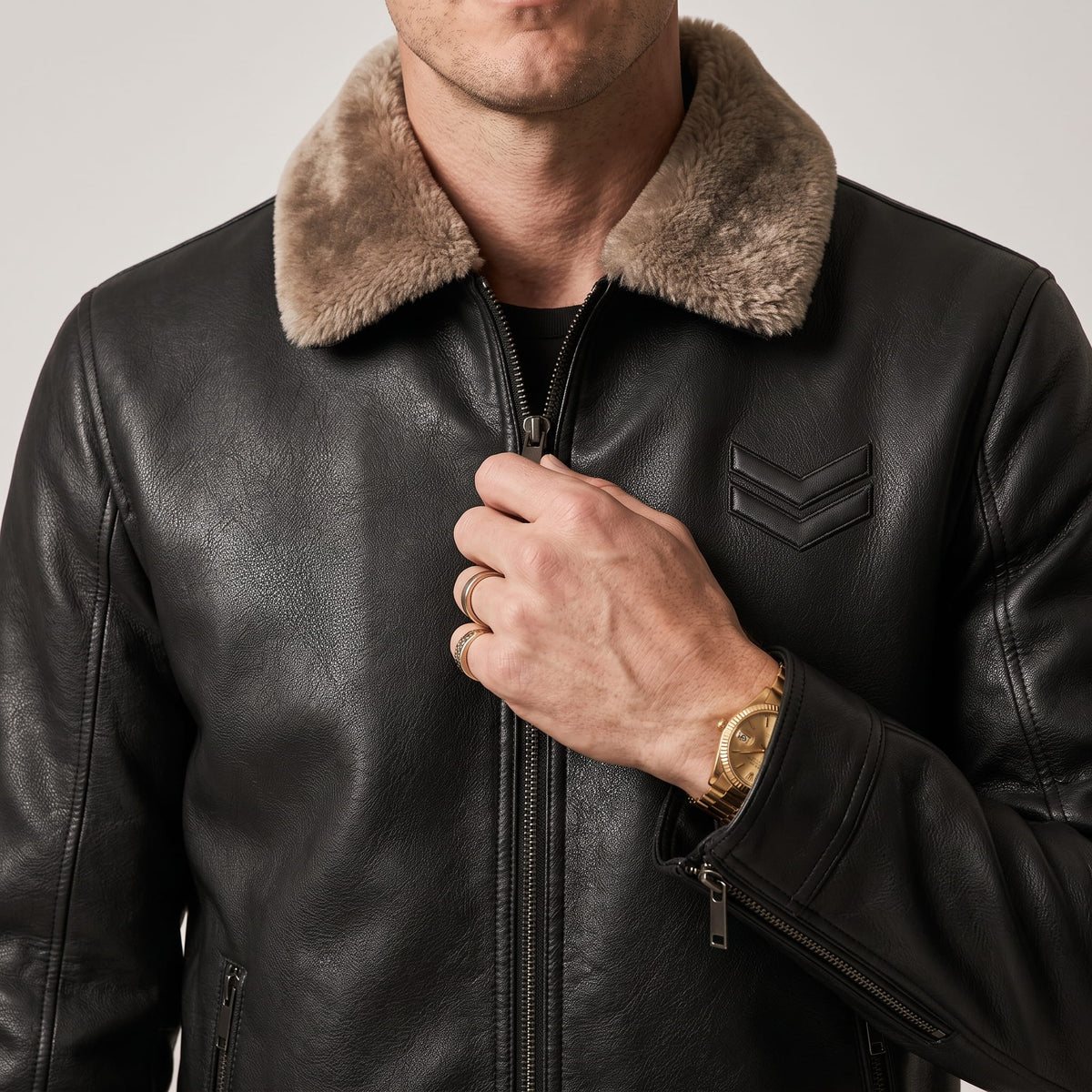 Close-up of a black leather shearling jacket showing the plush collar and full-zip front
