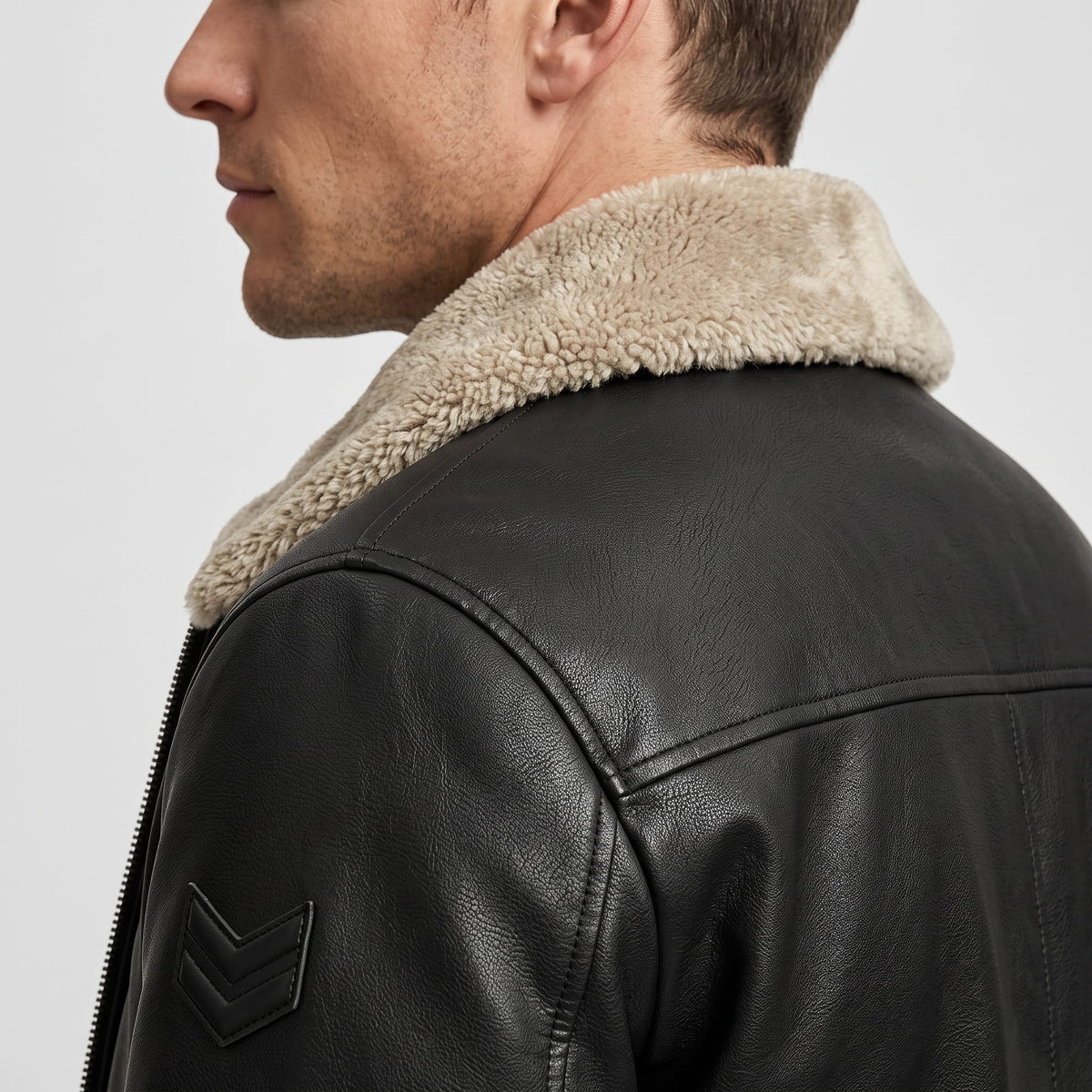Close-up side view of a black leather shearling jacket showing the plush collar and shoulder detail