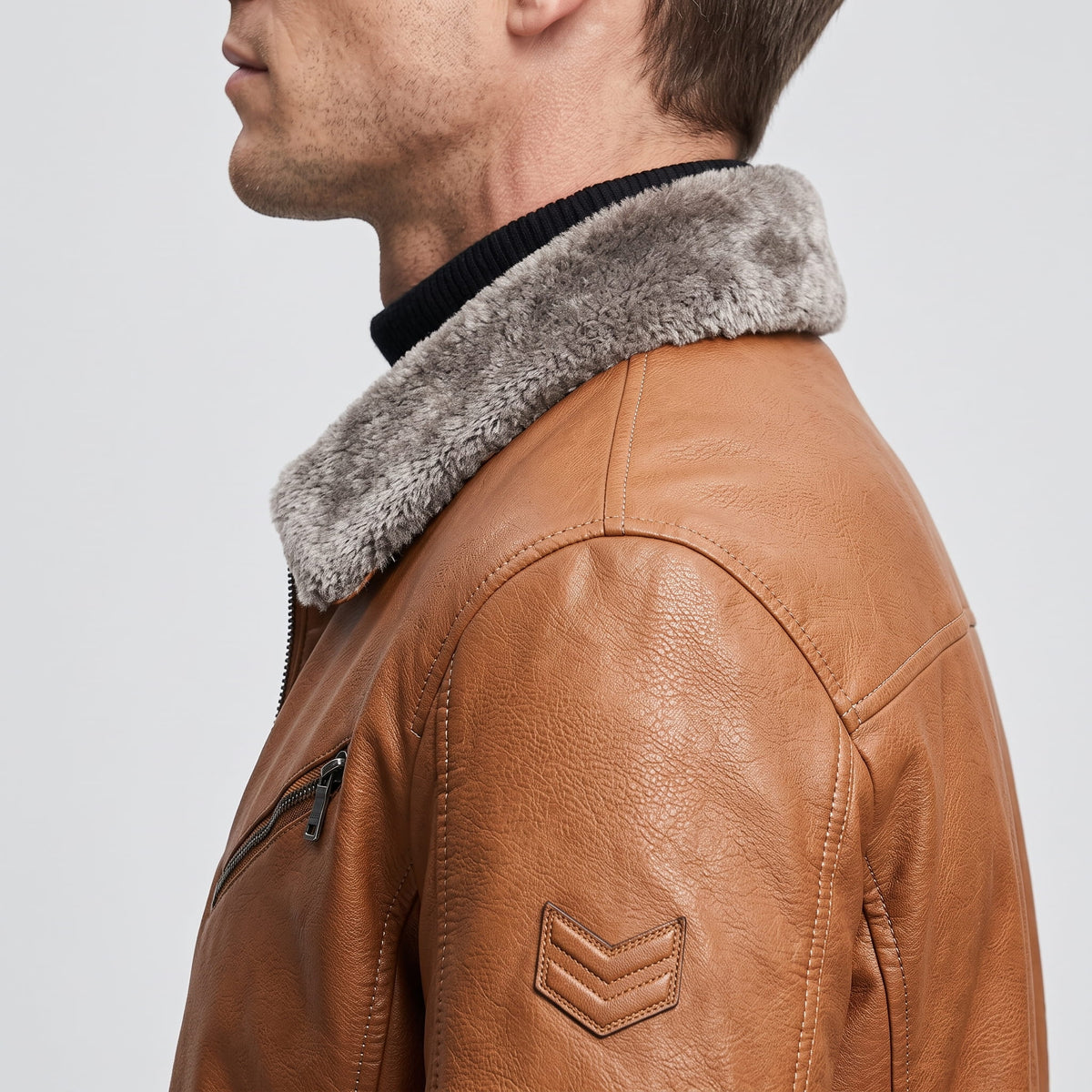 Close-up side view of a brown leather shearling jacket showing the plush collar and sleeve detail