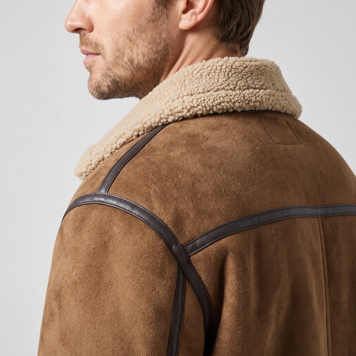 Close-up of a brown leather shearling jacket showing the sherpa-lined notched collar and shoulder detail