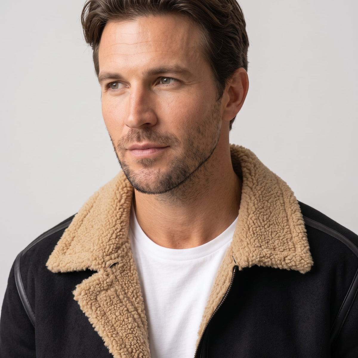 Close-up of a man wearing a black leather shearling jacket, showing the sherpa lining and notched collar
