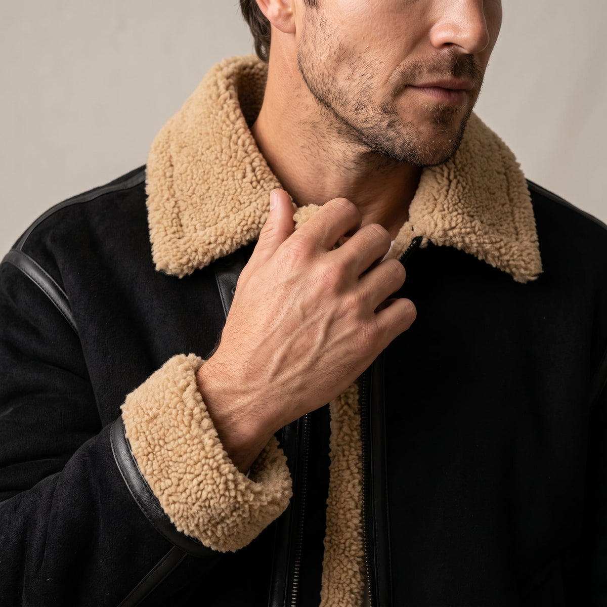 Close-up of a black leather shearling jacket showing the sherpa-lined notched collar and front detail