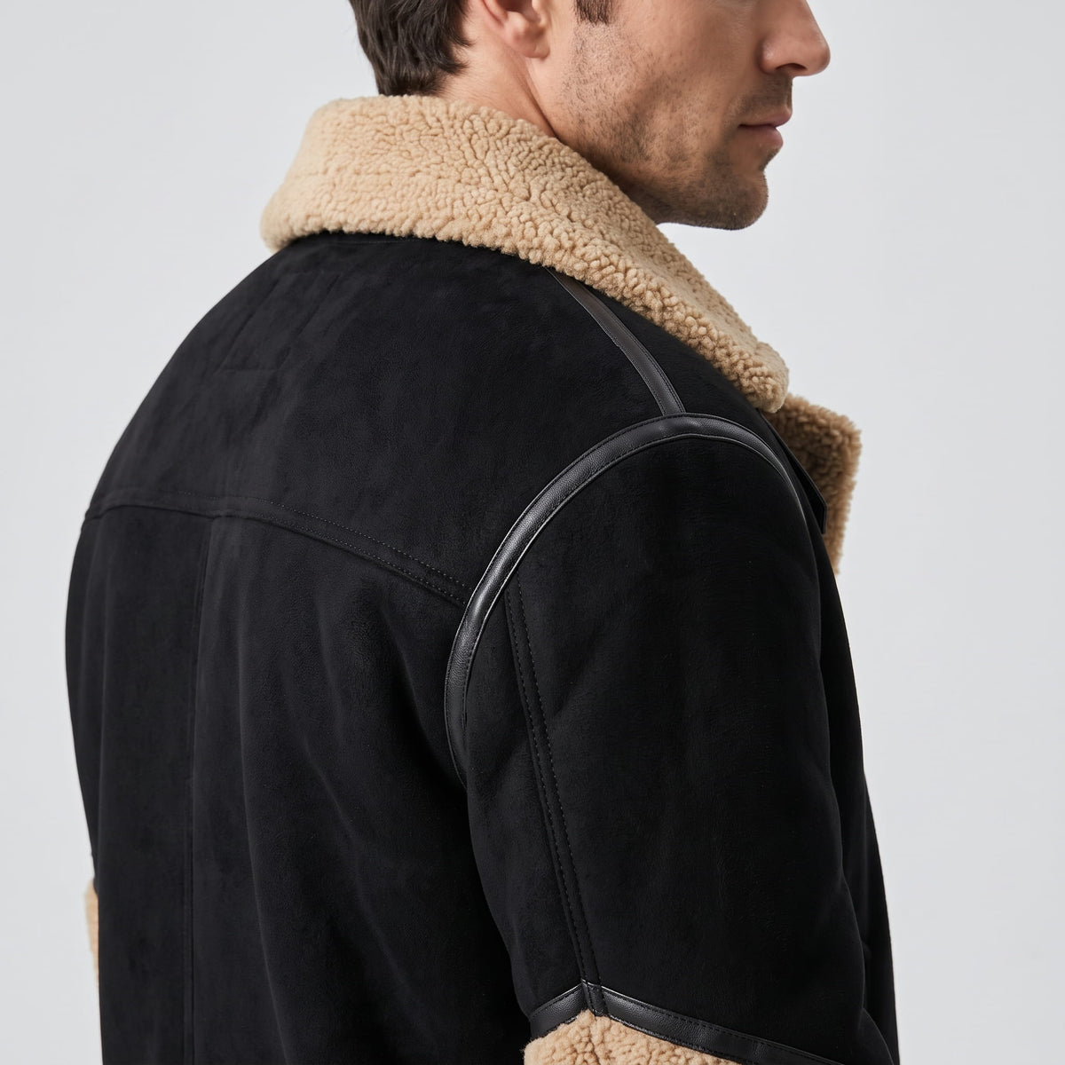 A man wearing a black leather shearling jacket with sherpa lining and a notched collar, shown from the side
