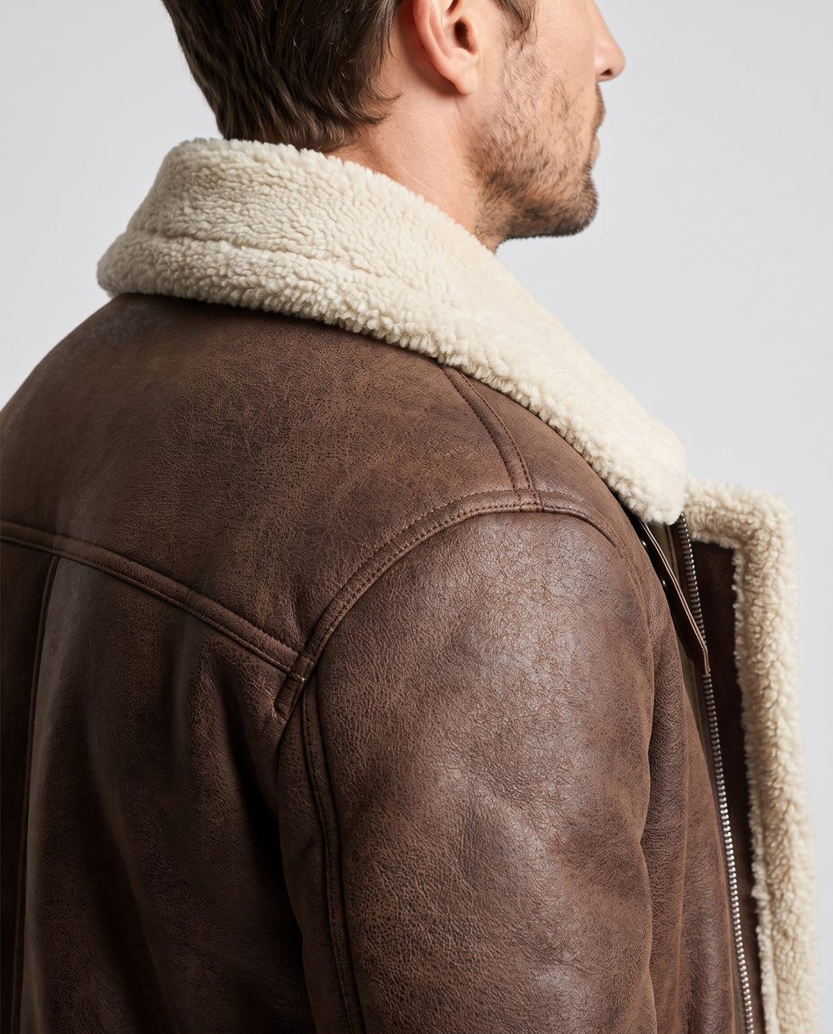 Close-up of a dark brown leather sherpa aviator jacket showing the fleece-lined collar and shoulder detail