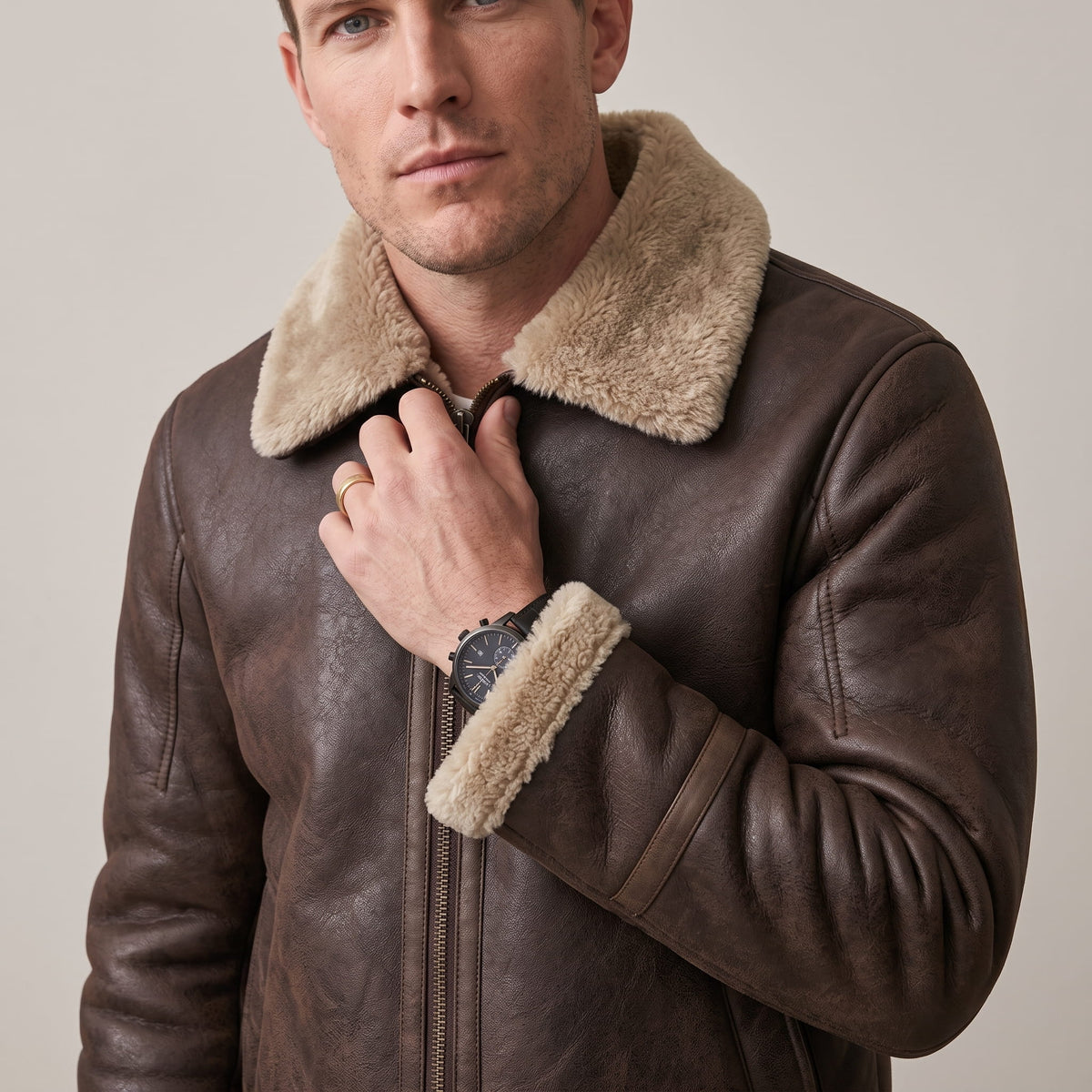 Close-up of a man wearing a dark brown leather sherpa aviator jacket, showing the fleece collar and front zip