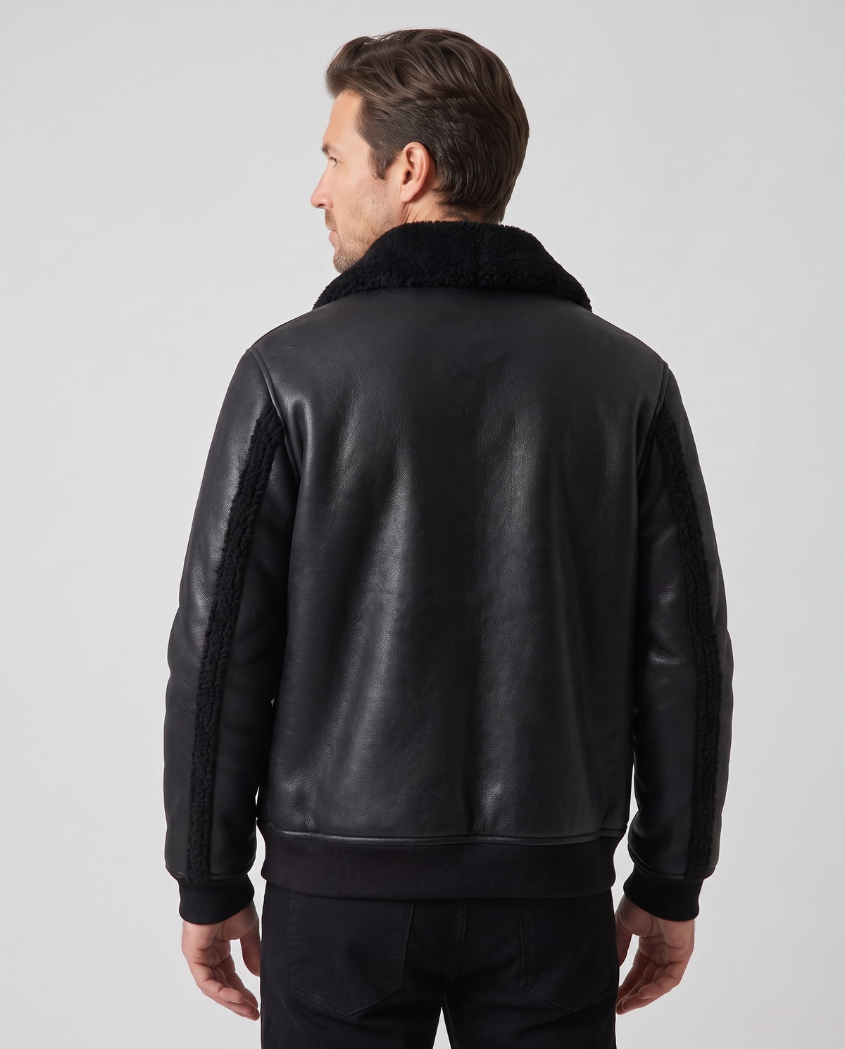 A man wearing a black leather sherpa aviator jacket with a wide collar and ribbed trim, shown from the back