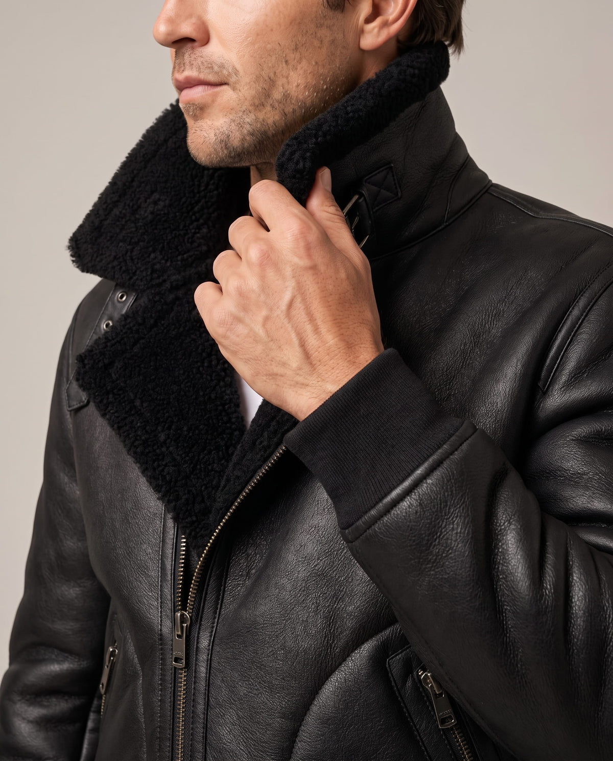 Close-up of a man wearing a black leather sherpa aviator jacket, showing the wide plush collar and front detail