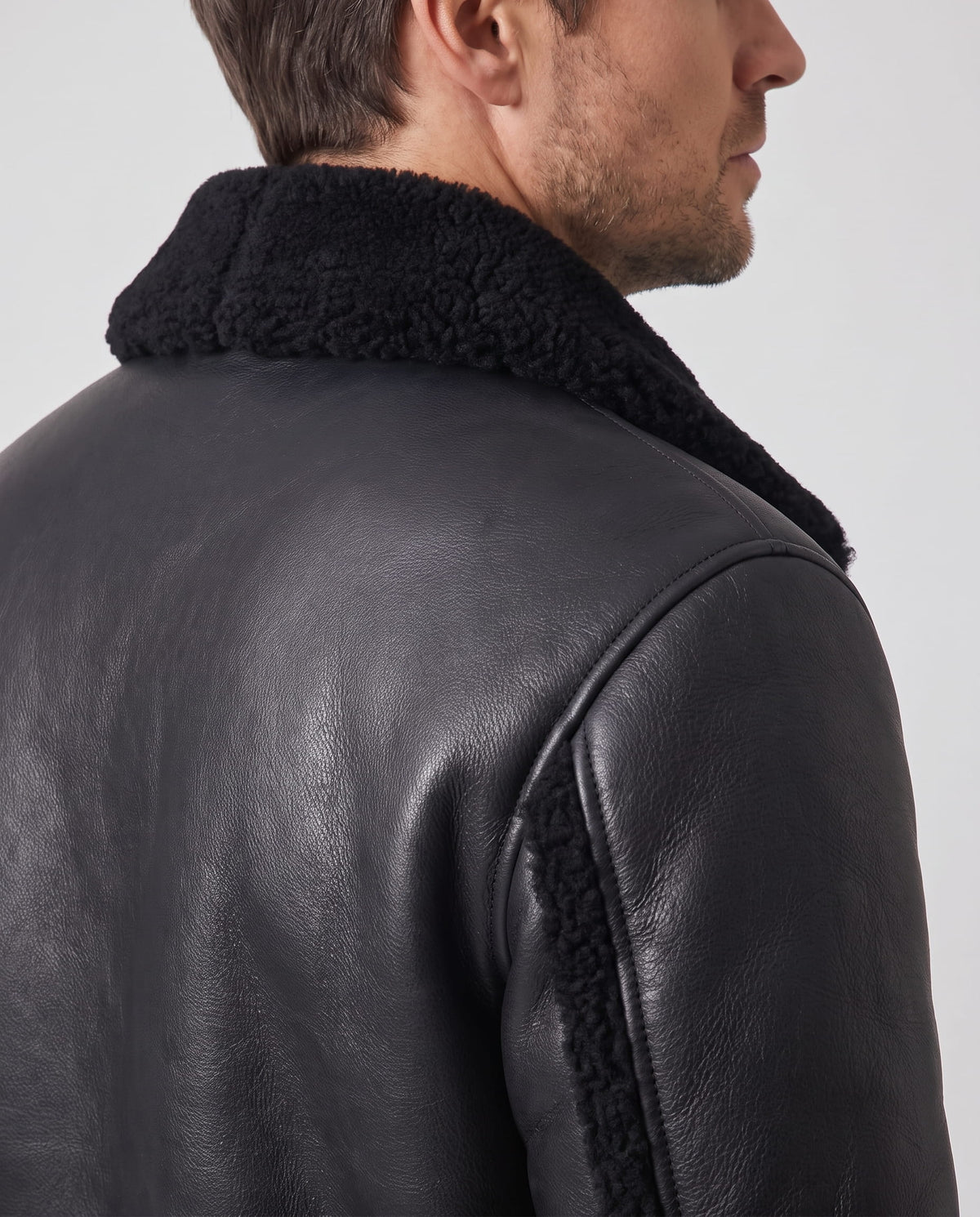 Close-up side view of a black leather sherpa aviator jacket showing the wide collar and back detail
