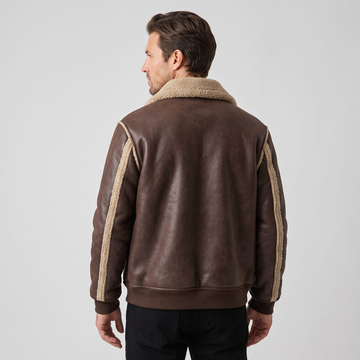A man wearing a brown leather sherpa aviator jacket with a wide collar and ribbed trim, shown from the back