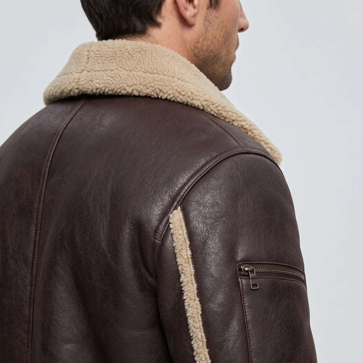 Close-up side view of a brown leather sherpa aviator jacket showing the wide collar and sleeve detail