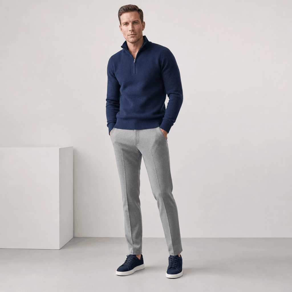 Full-body view of the man wearing the navy blue half-zip sweater with light-colored pants.