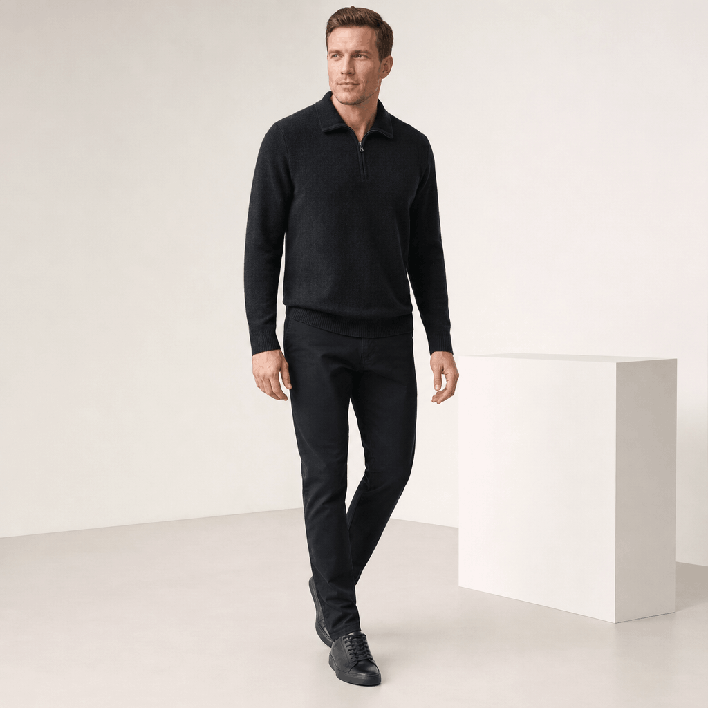 Full-body view of the man wearing the black half-zip sweater with black pants.
