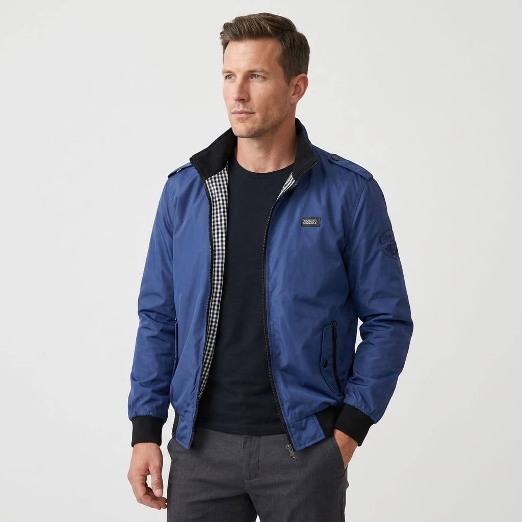 Man wearing a navy blue bomber jacket with dark trousers and white sneakers.