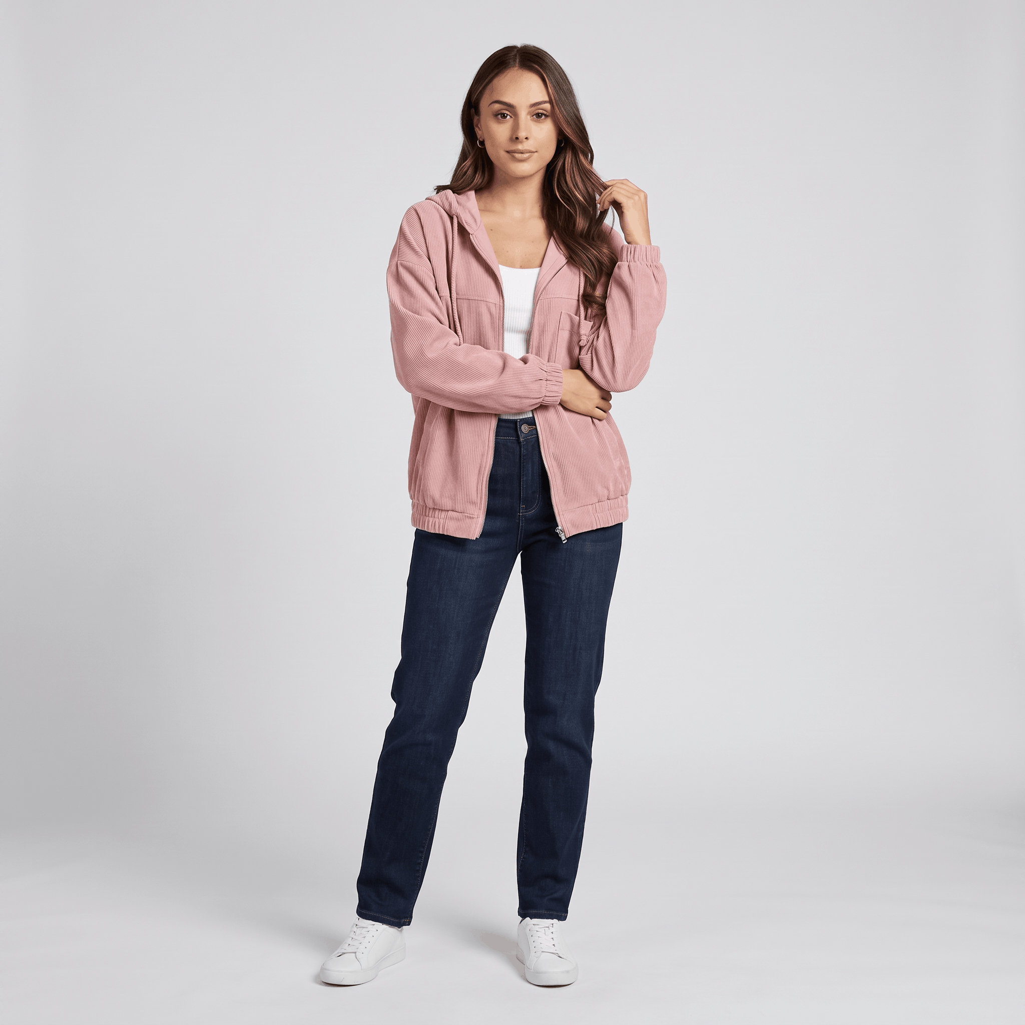 Dusty pink corduroy zip-up hoodie with a drawstring hood, elasticated cuffs, and a relaxed fit worn over a white top.