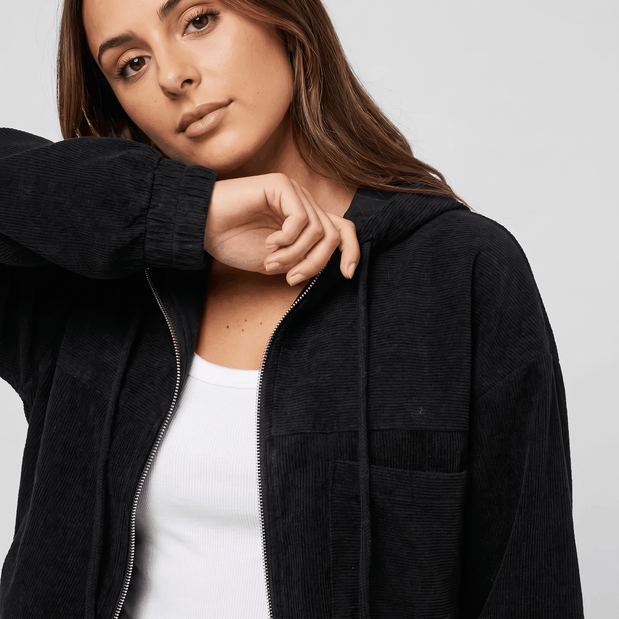 Black corduroy zip-up hoodie with a textured ribbed surface, drawstring hood, and relaxed fit over a white base layer.