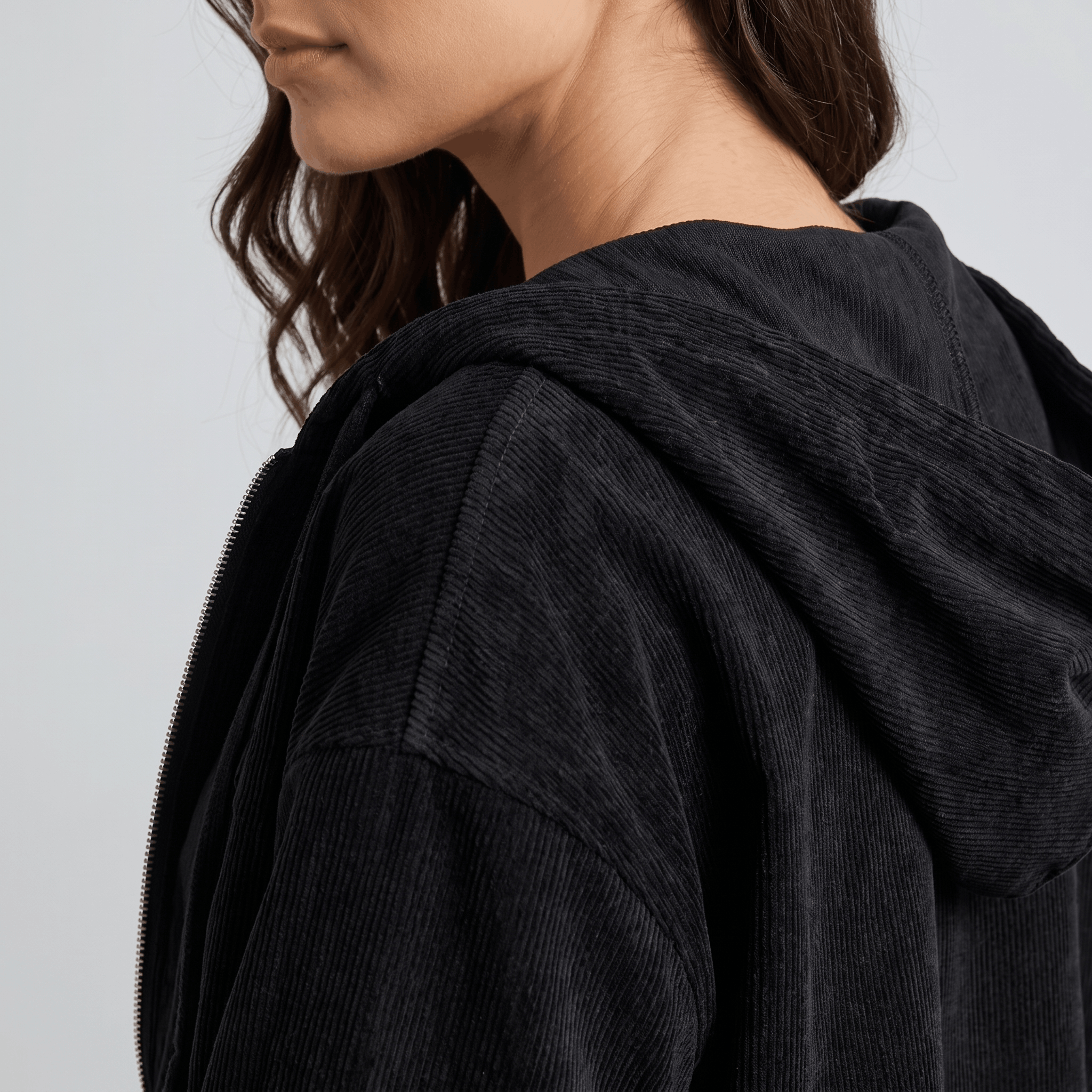 Black corduroy zip-up hoodie with a textured wale surface, drawstring hood, and relaxed layering fit.