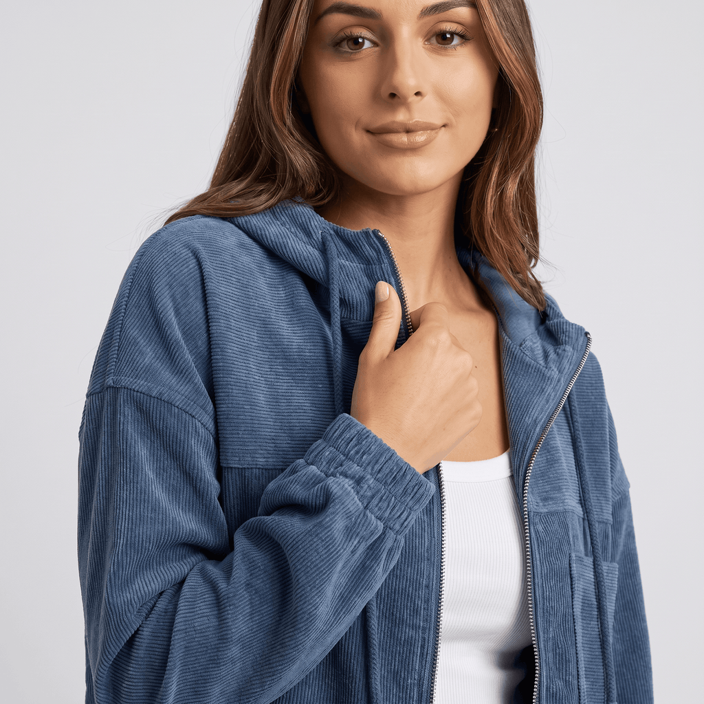 Washed blue corduroy zip-up hoodie with a textured ribbed surface, drawstring hood, and elasticated cuffs.