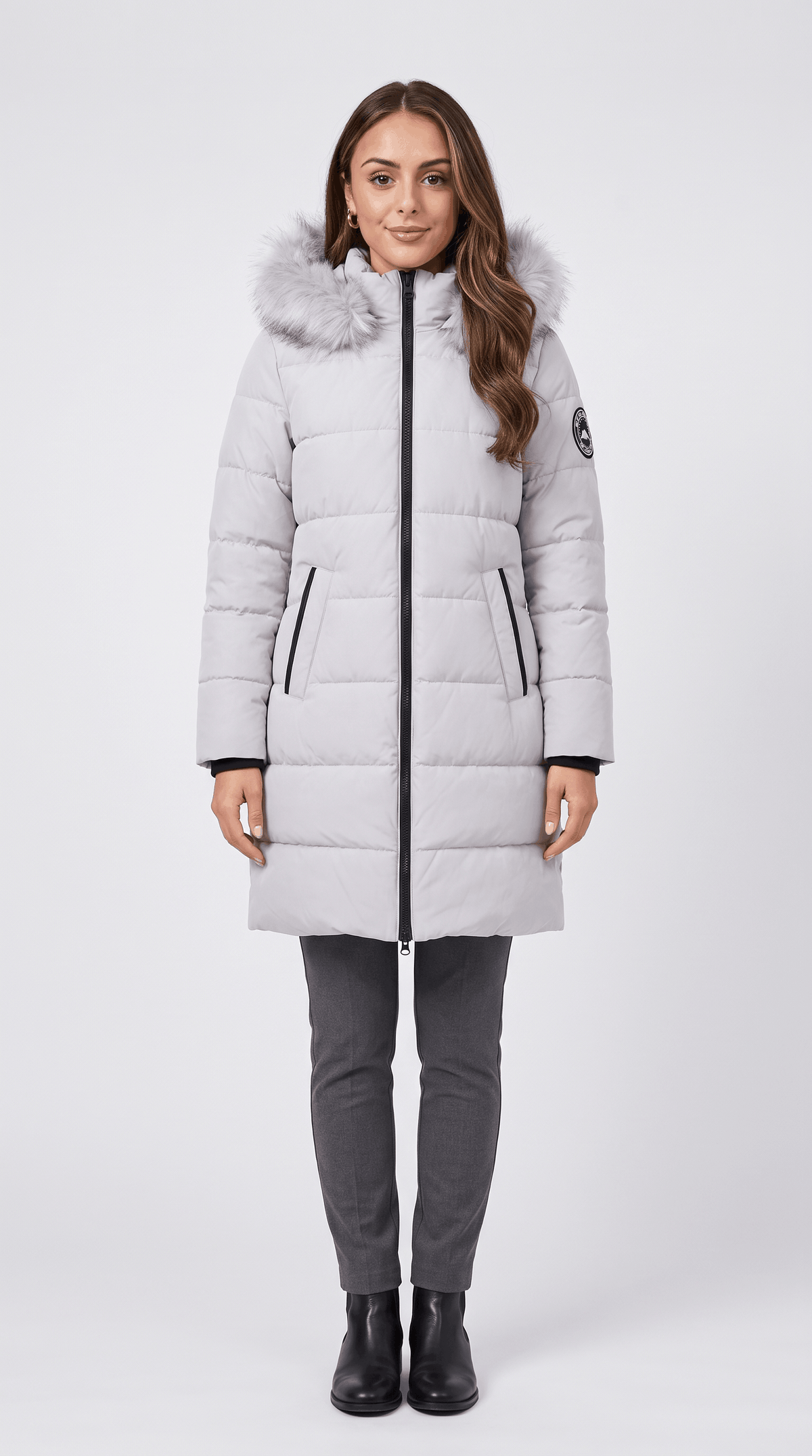 A woman wearing a light gray long insulated parka jacket with a hood and full-zip front
