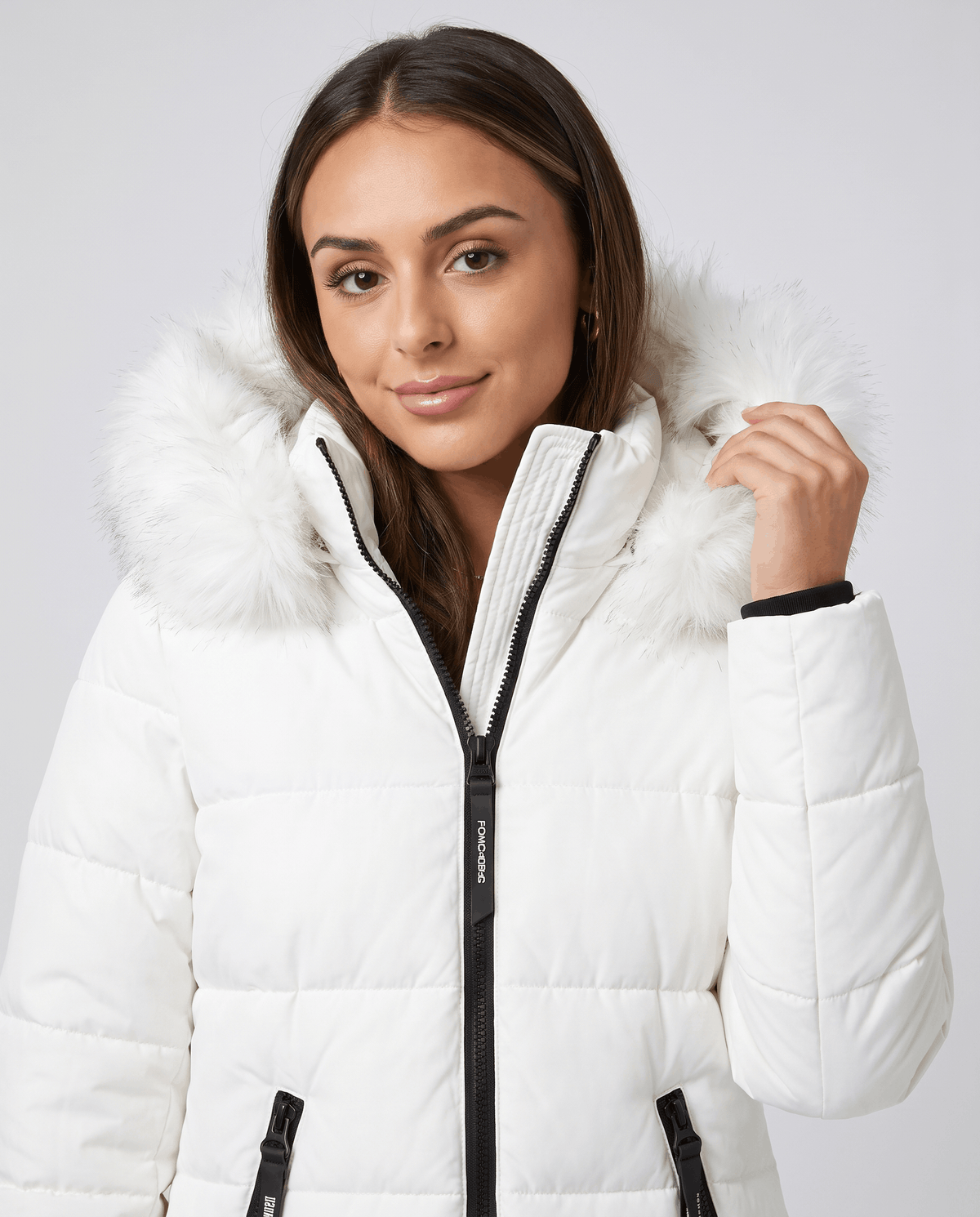 Close-up of a woman wearing a white long insulated parka jacket, showing the hood and full-zip front
