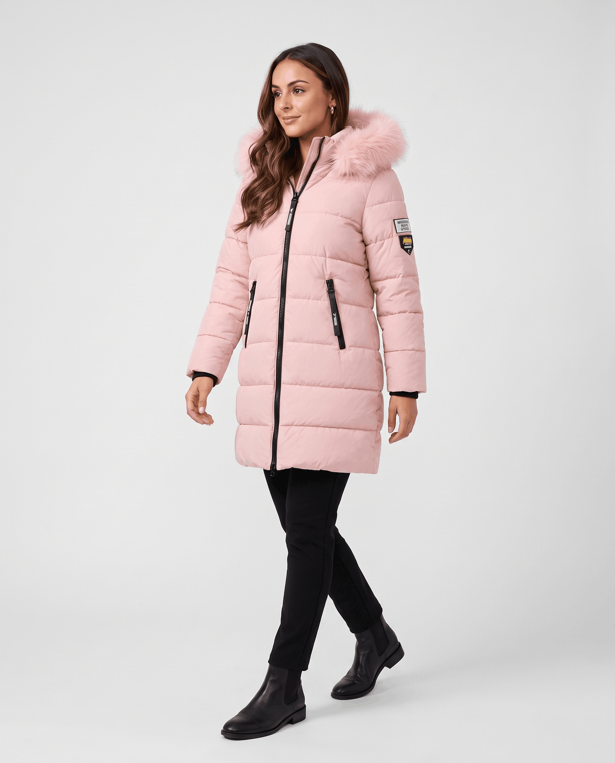 A woman wearing a long pink insulated parka jacket with a hood and full-zip front