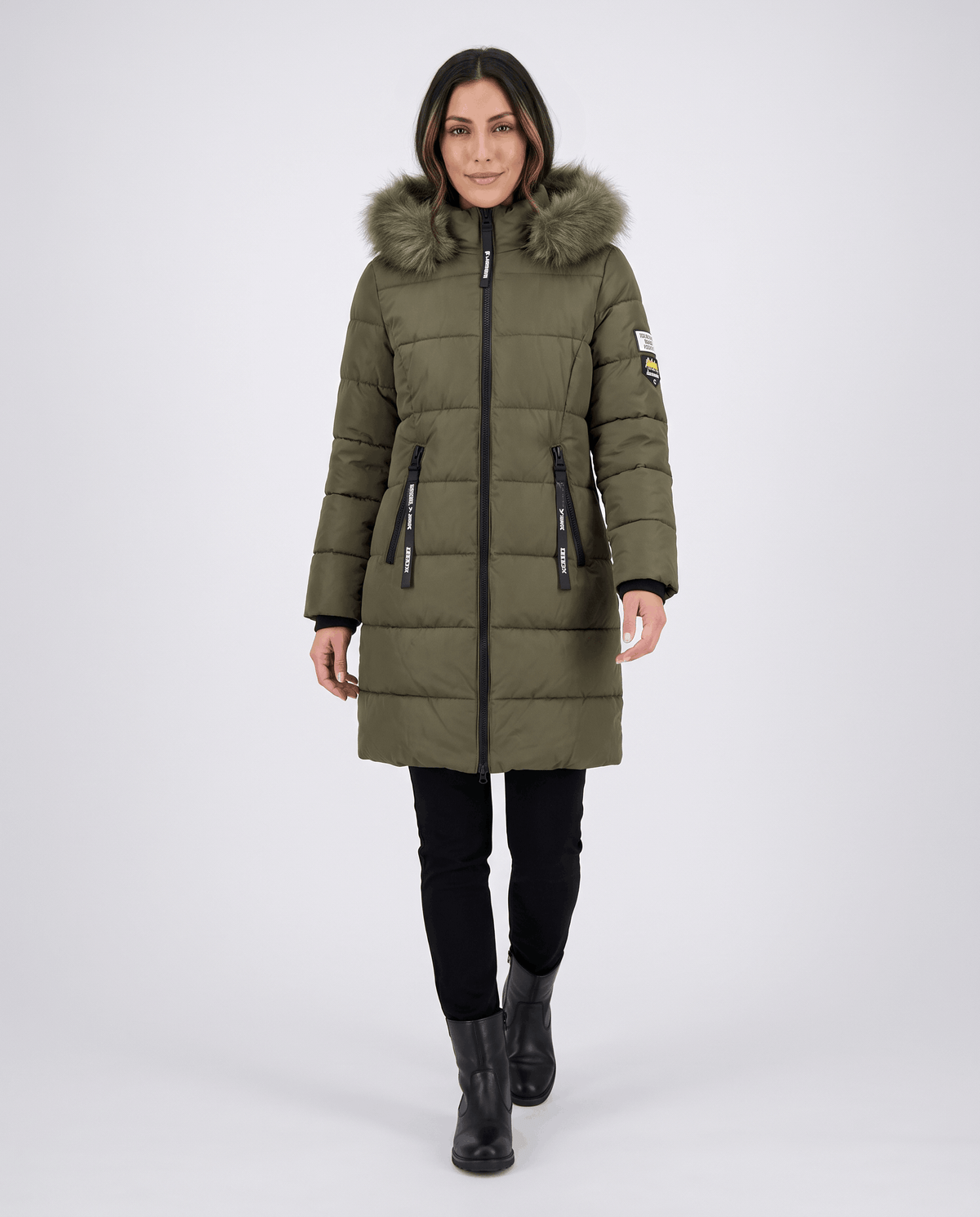 A woman wearing a long olive green parka jacket with an insulated design, hood, and full-zip front