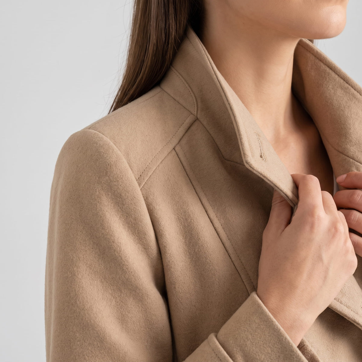 Close-up of a woman wearing a beige trench coat, showing the collar and double-breasted front