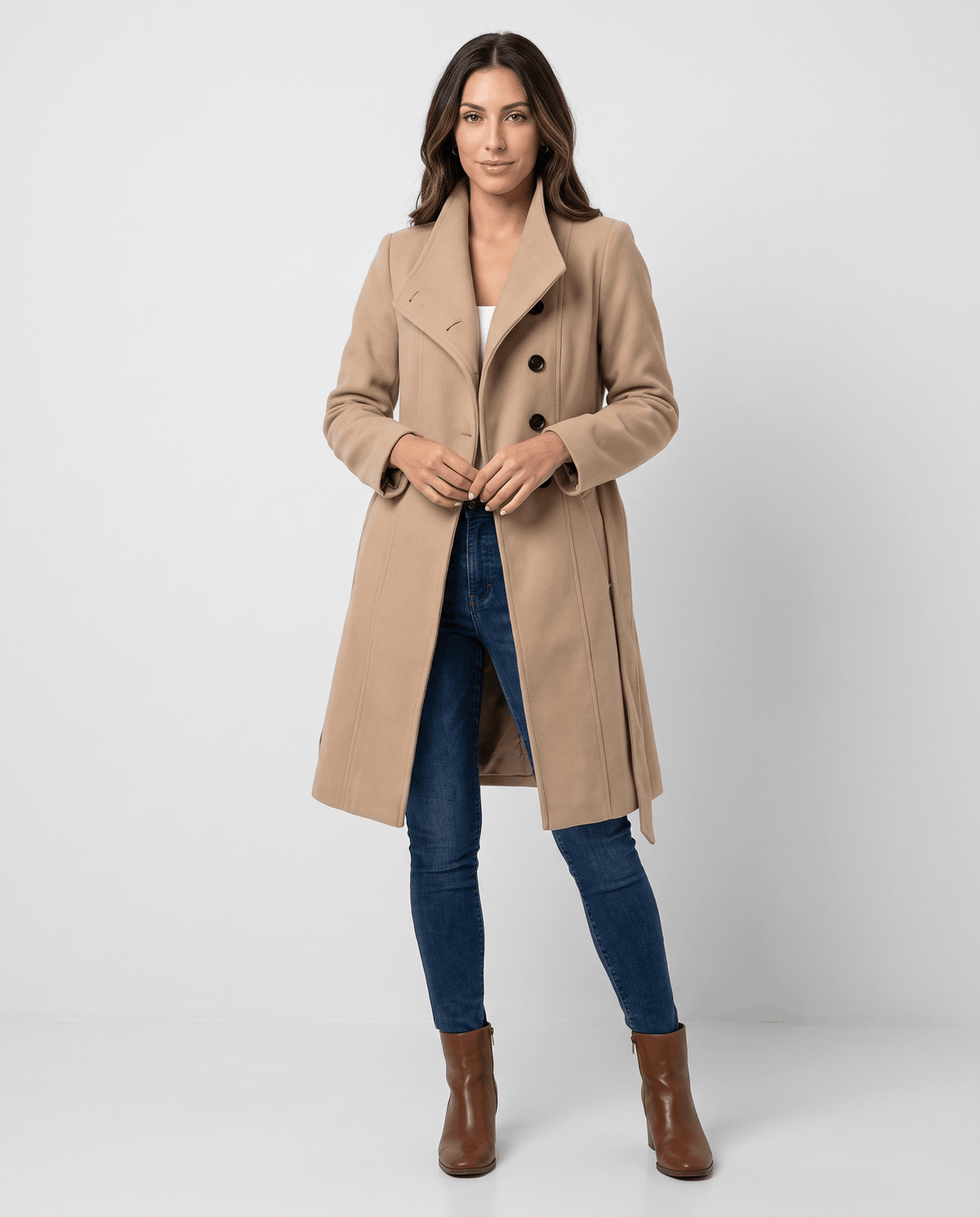 A woman wearing a long beige trench coat with a belted waist and double-breasted front
