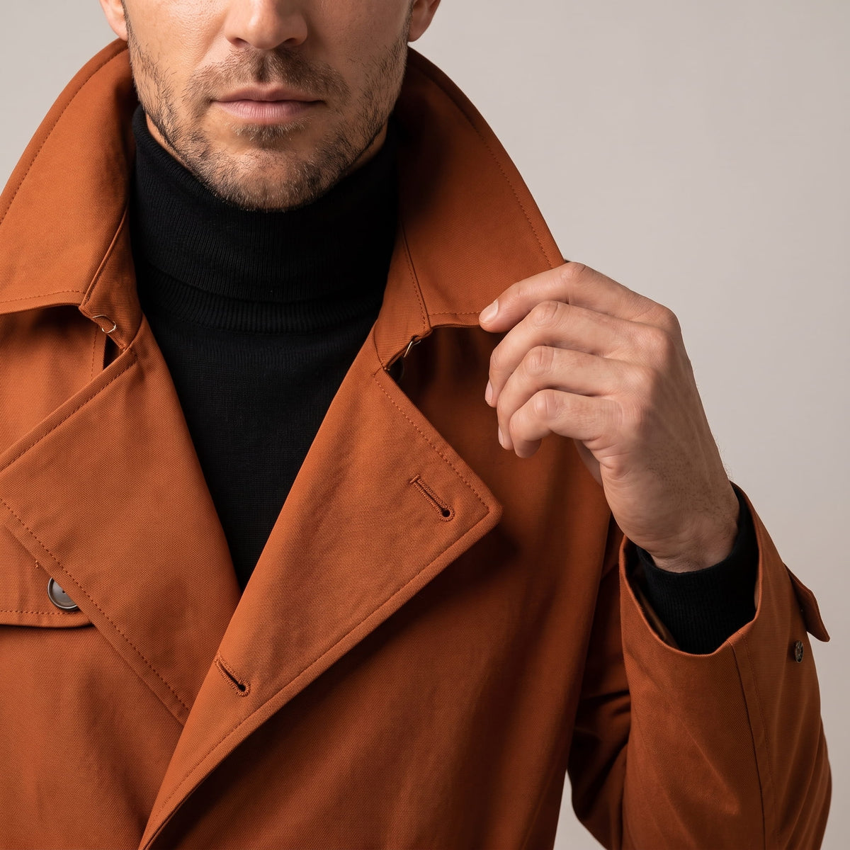 Close-up of a man wearing an orange double-breasted trench coat, showing the wide lapels, collar, and front buttons