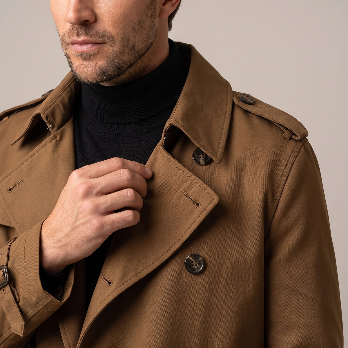 Close-up of a man wearing a brown double-breasted trench coat, showing the wide lapels and front buttons