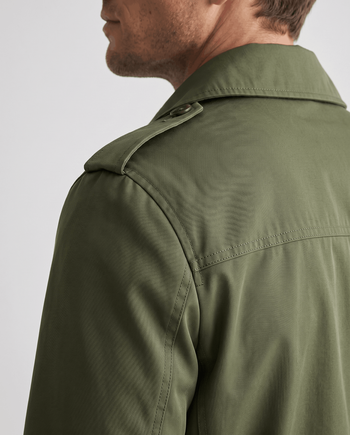 Close-up of an olive green trench coat showing the structured collar and shoulder detail