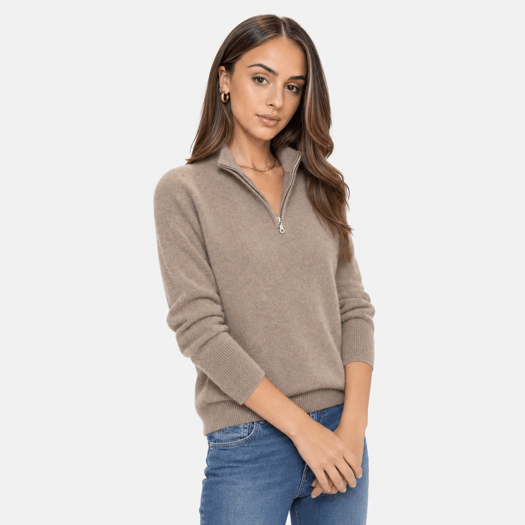 Woman wearing a taupe ribbed half-zip sweater with blue jeans, shown in a relaxed standing pose.