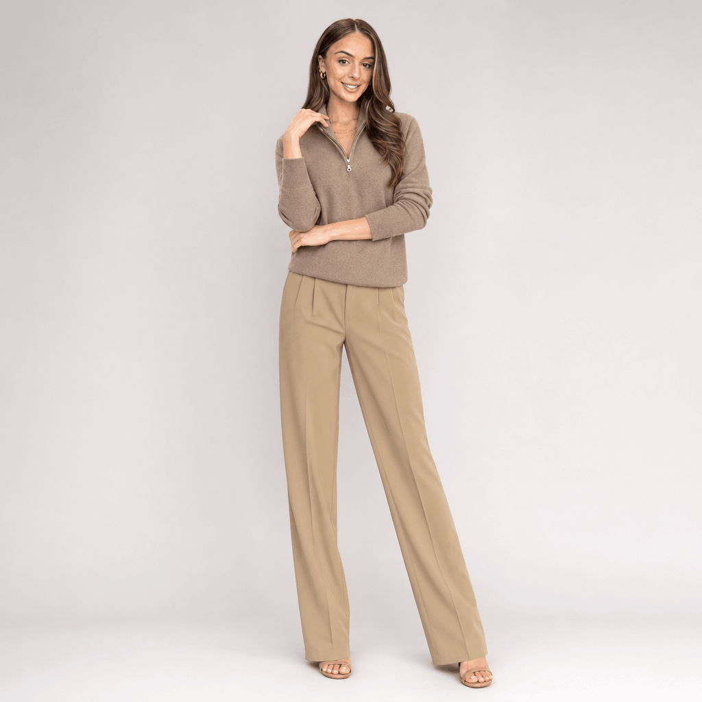 Full-body view of the woman wearing the taupe ribbed half-zip sweater with beige pants.
