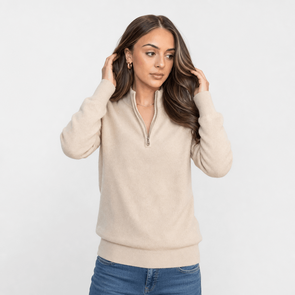 Woman wearing a cream ribbed half-zip sweater with blue jeans, shown in a relaxed pose.