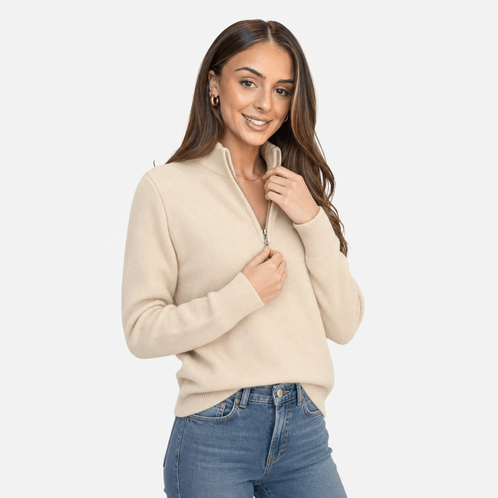 Woman wearing a cream ribbed half-zip sweater with blue jeans, shown in a relaxed pose.