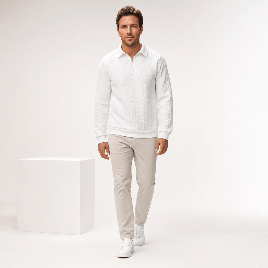 Full-body view of the man wearing the white cable-knit quarter-zip sweater with matching light trousers and white sneakers.