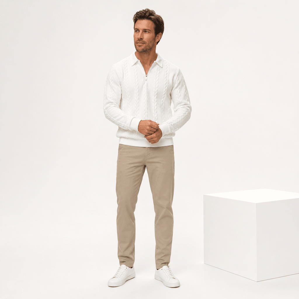 Man wearing a black cable-knit quarter-zip sweater with gray trousers and white sneakers.