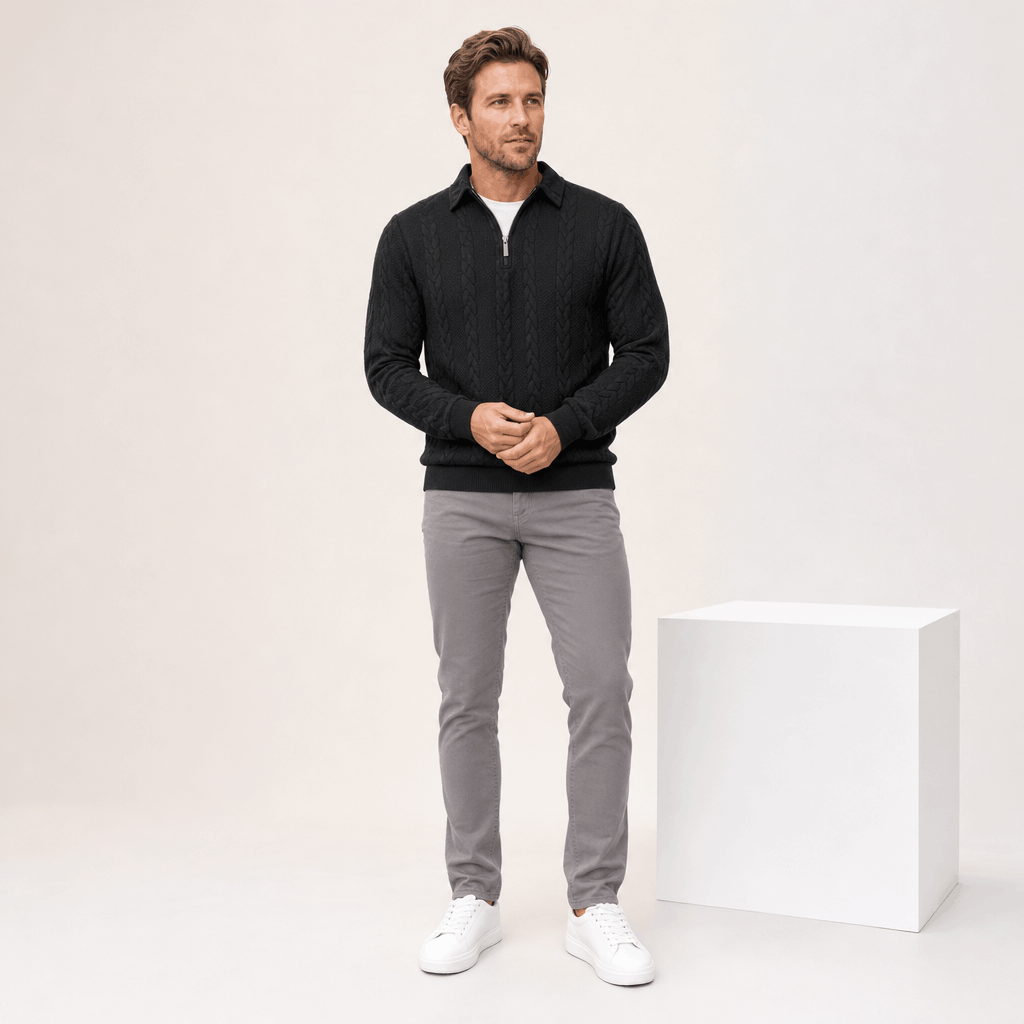 Full-body view of the man wearing the black cable-knit quarter-zip sweater with gray trousers.