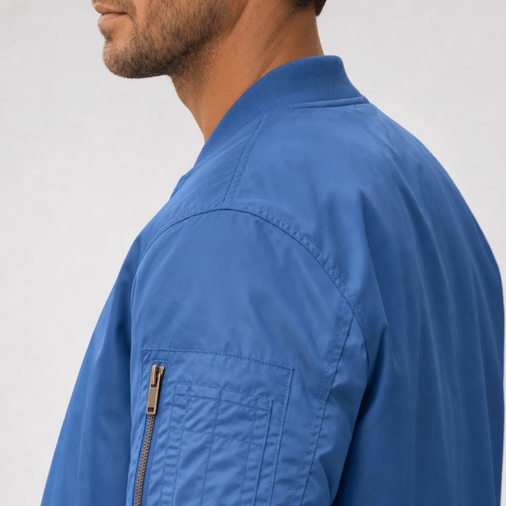 Close-up back and side view of the blue bomber jacket, highlighting the shoulder and zippered sleeve pocket.