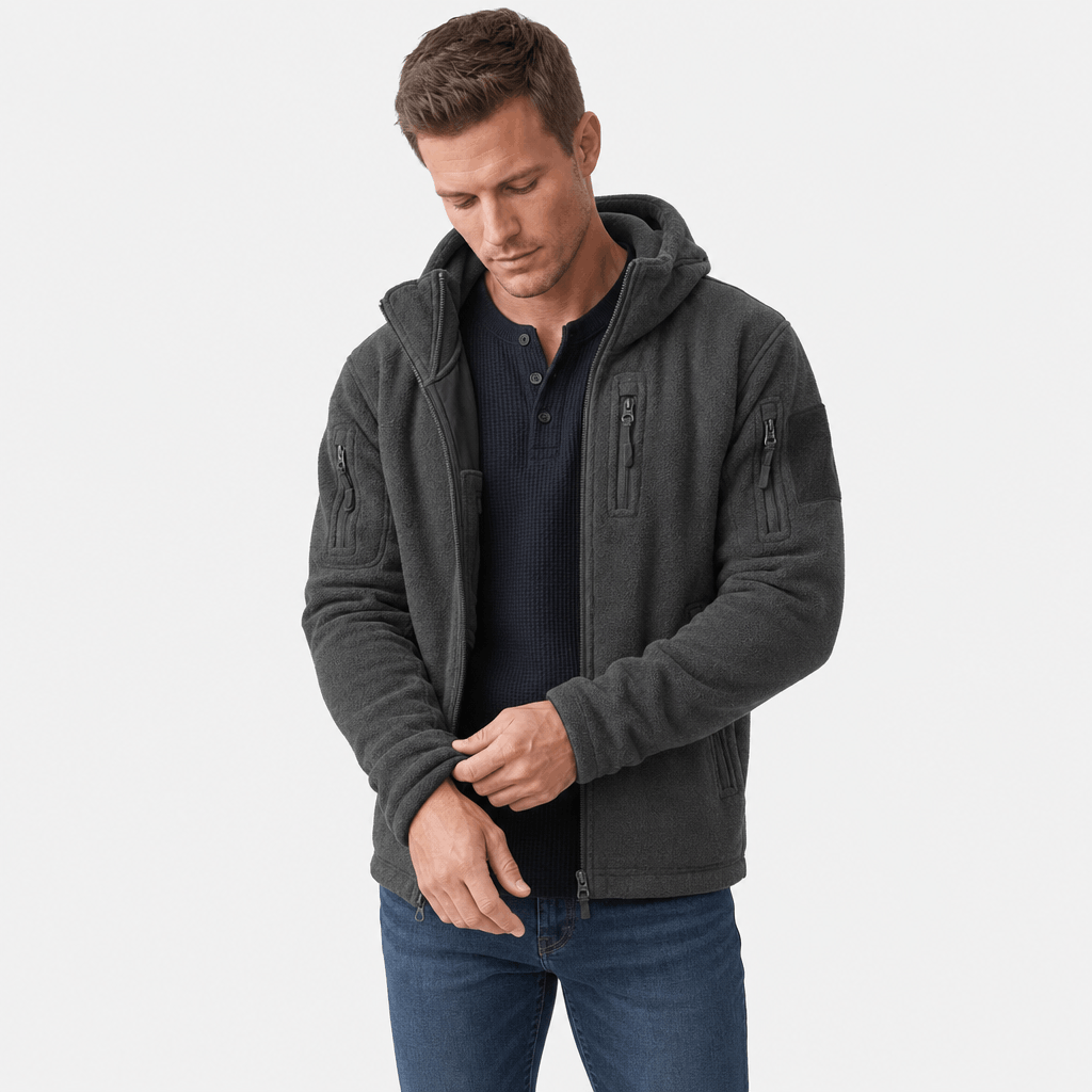 Male model wearing a dark charcoal hooded zip-up jacket with hands near the front zipper.