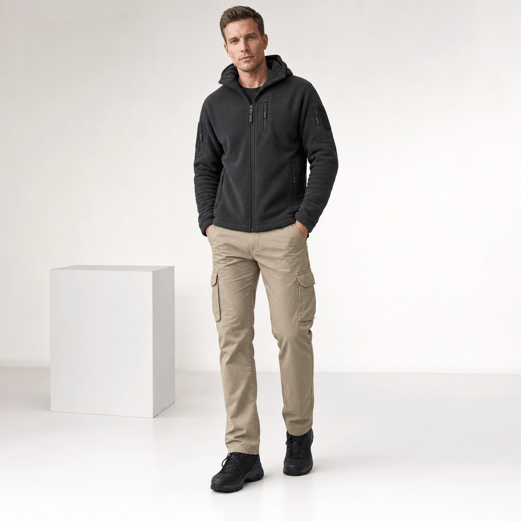 Male model wearing the dark charcoal hooded zip-up jacket with light-colored pants.