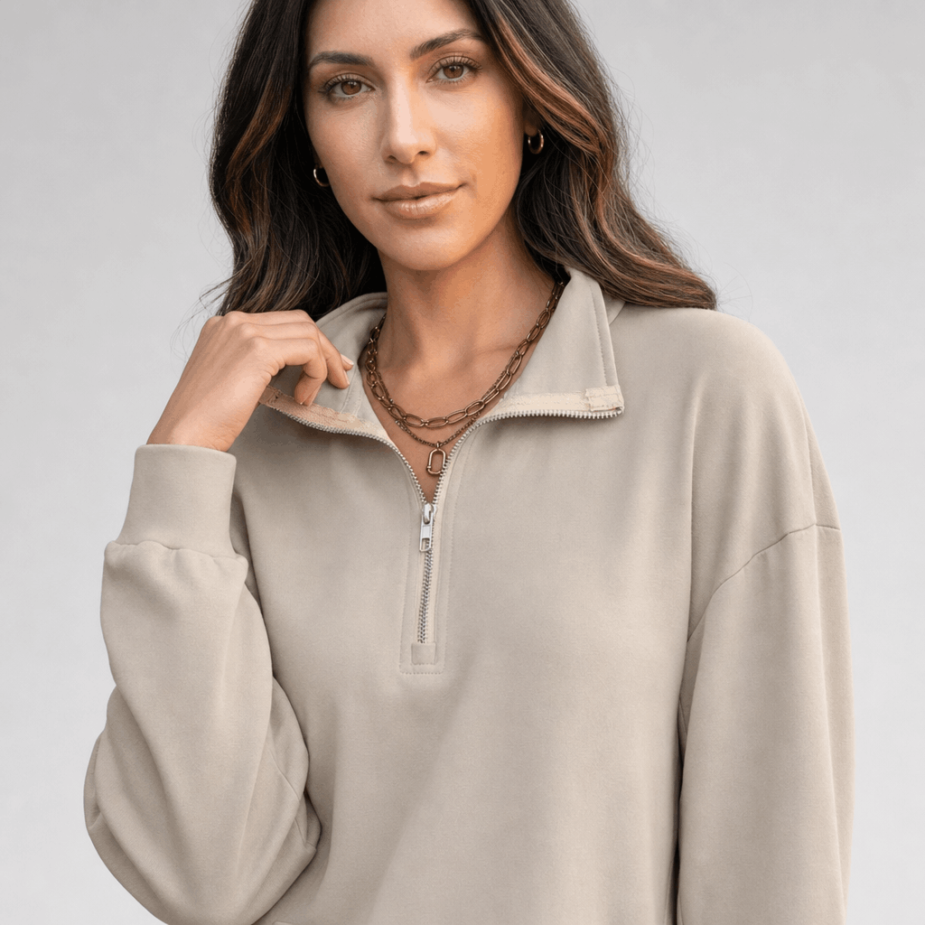 Close-up of the light taupe quarter-zip sweater, highlighting the zipper, raised collar, and soft knit texture.