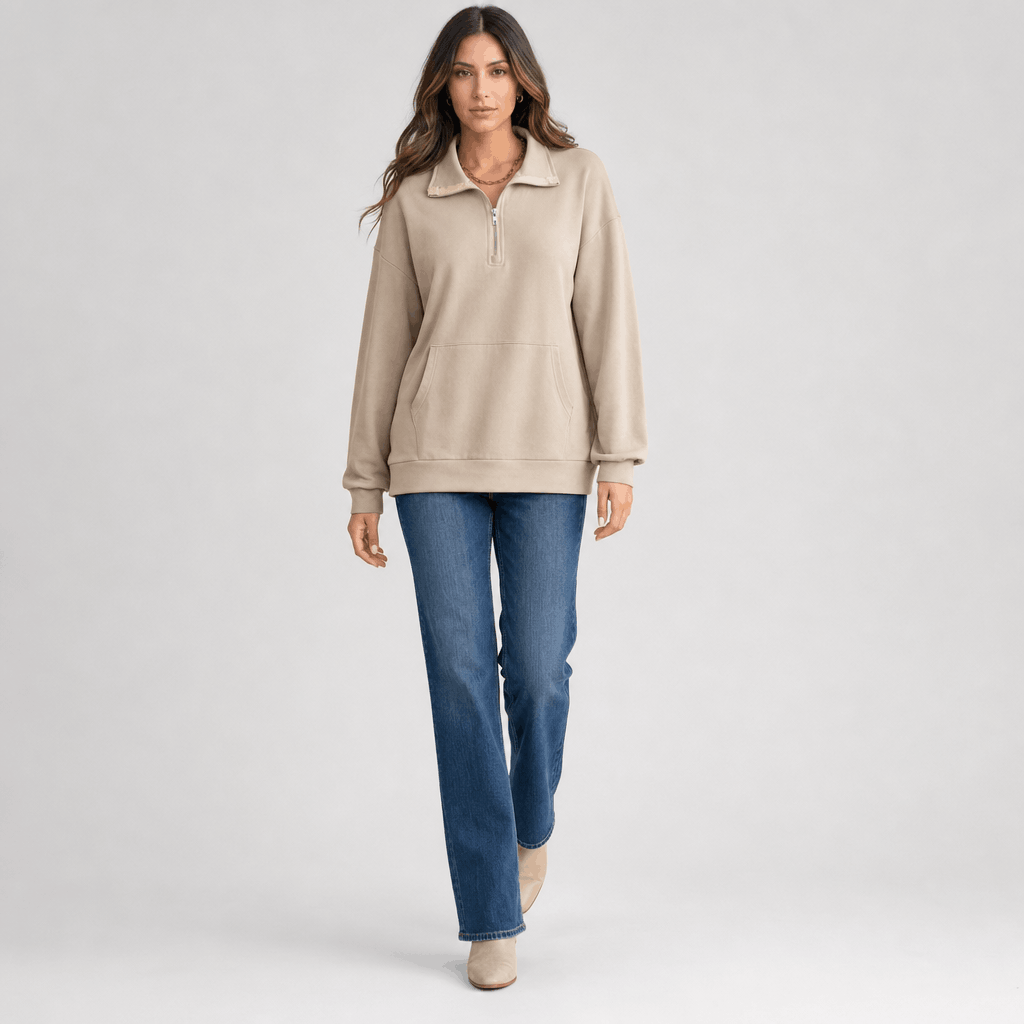 Full-body view of a female model wearing the light taupe quarter-zip sweater with blue jeans.