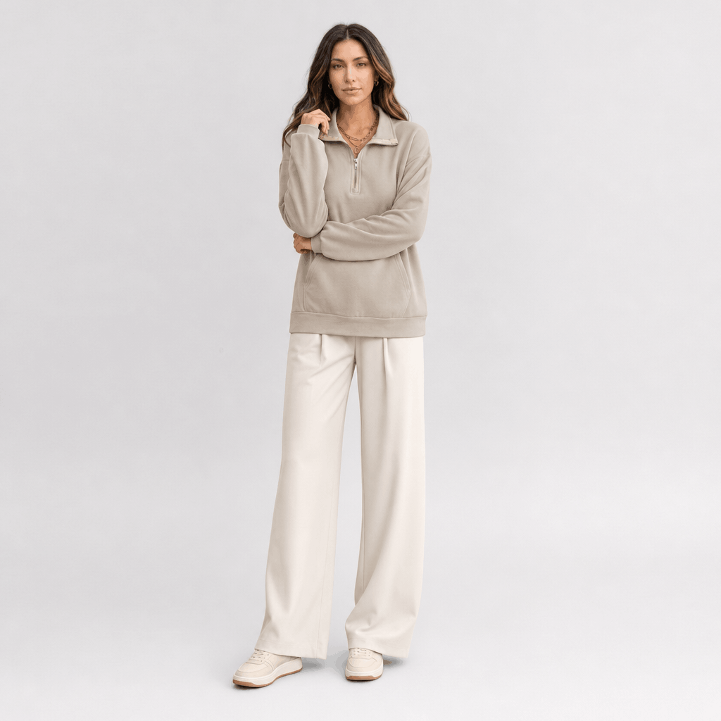 Full-body view of a female model wearing the light taupe quarter-zip sweater with light-colored trousers.