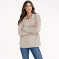 Female model wearing a light taupe quarter-zip sweater with a relaxed fit, paired with blue jeans, arms crossed.