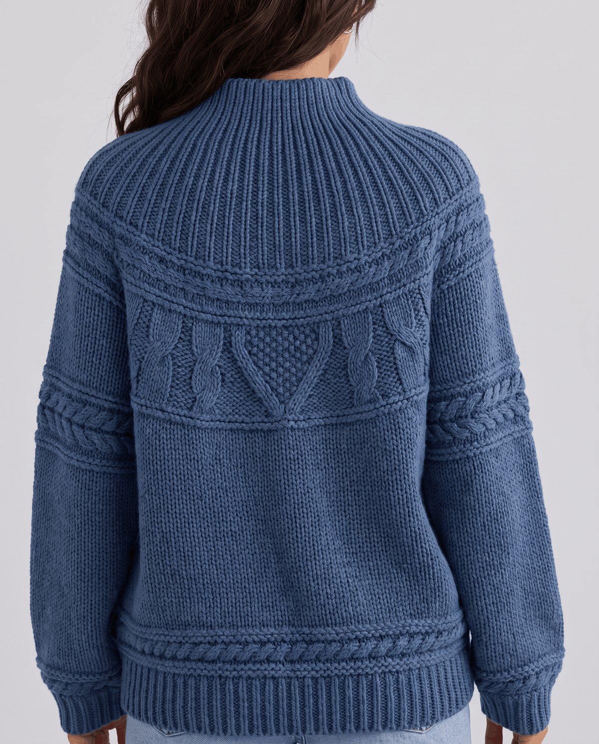 Blue Merino Wool Cable Knit Sweater worn by a female model from the back, showcasing the textured cable knit pattern, relaxed fit, high neckline, and ribbed hem.
