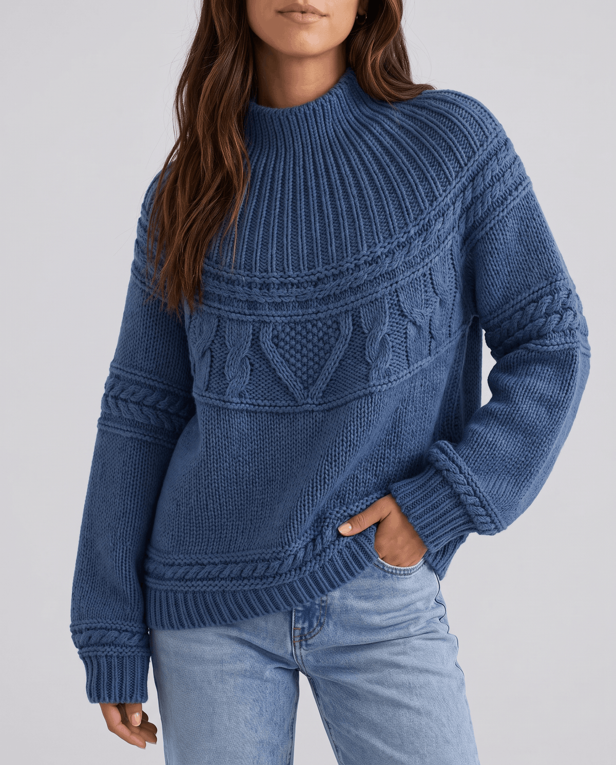 Blue Merino Wool Cable Knit Sweater worn by a female model with jeans, featuring a relaxed fit, textured cable knit pattern, high neckline, long sleeves, and ribbed trim.