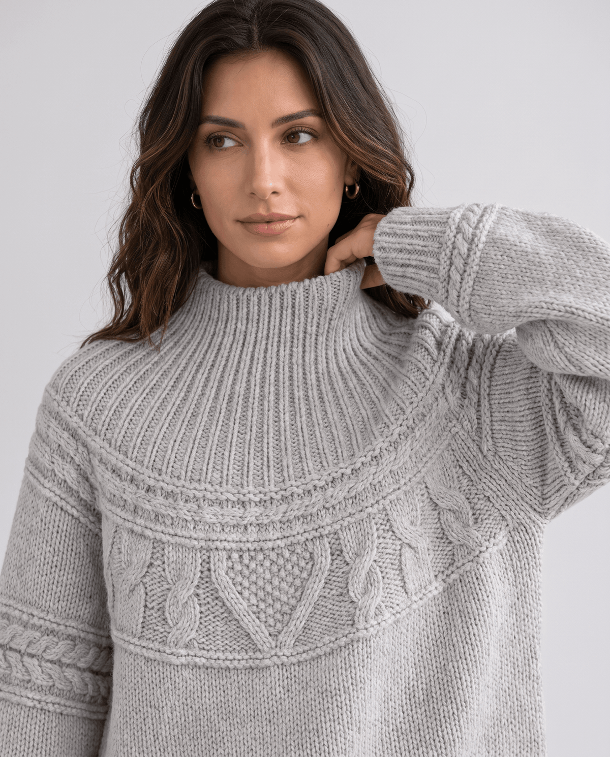 Gray Merino Wool Cable Knit Sweater worn by a female model, shown in close-up with a high neckline, cable knit texture, relaxed fit, and long sleeves.
