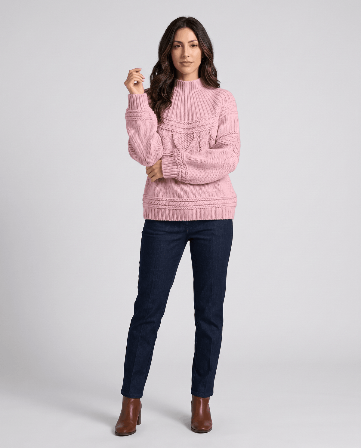 Pink Merino Wool Cable Knit Sweater worn by a female model with blue jeans, featuring a relaxed fit, textured cable knit pattern, high neckline, long sleeves, and ribbed trim.