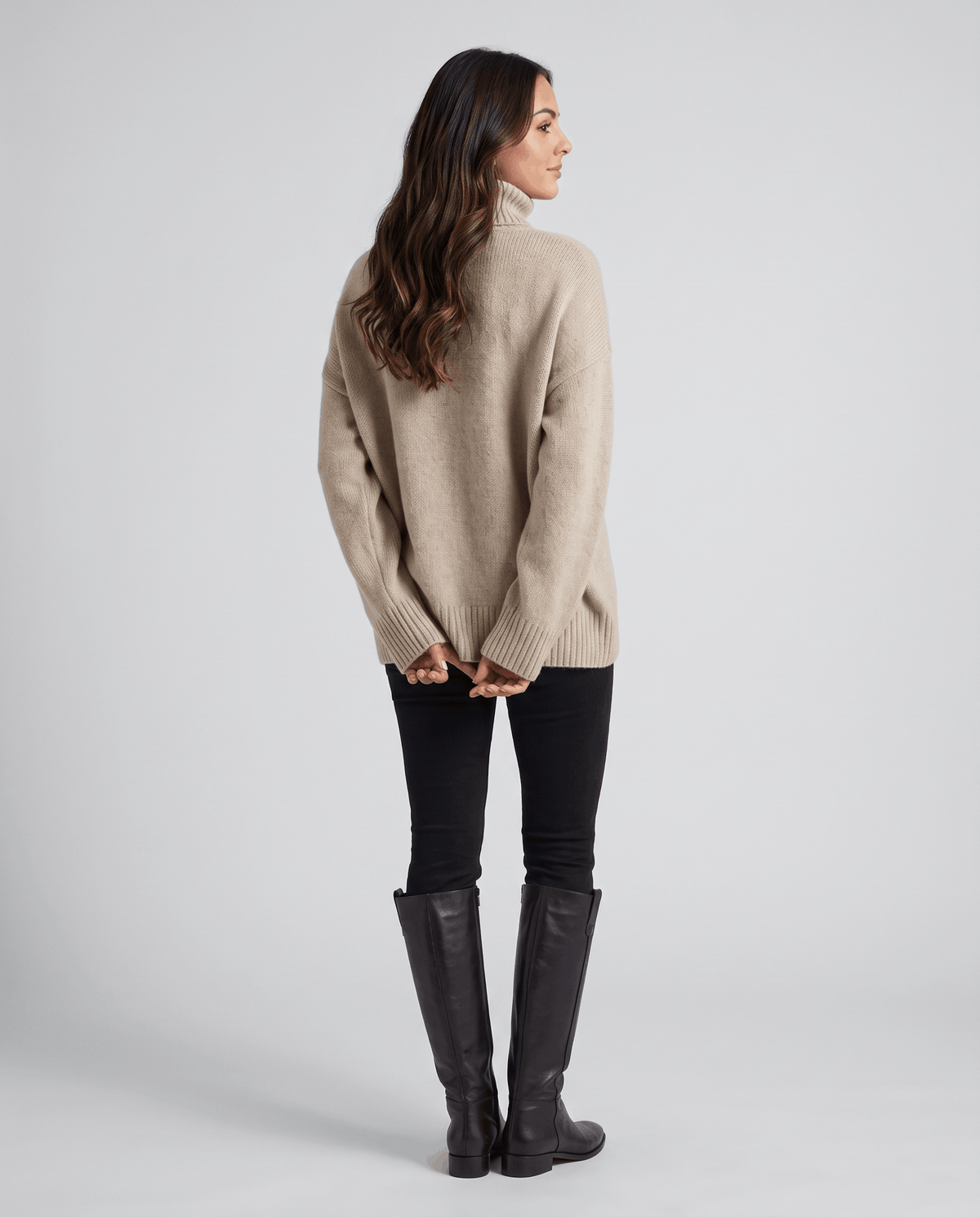 Dark Beige Merino Wool Turtleneck Sweater worn by a female model from the side, showcasing the oversized fit, high turtleneck collar, and relaxed silhouette.
